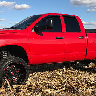Lifted red Ram in farm field